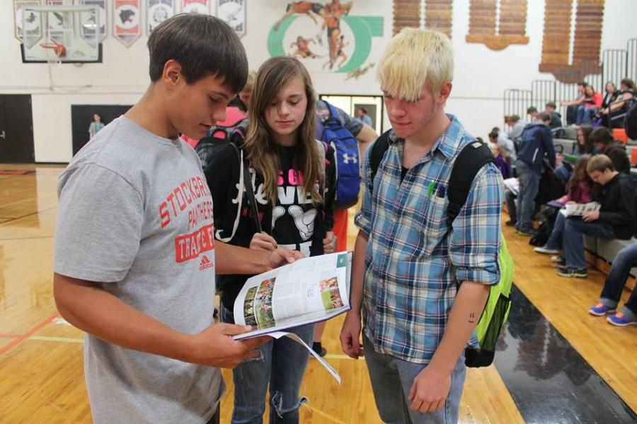 Sophomores C. Hendrickson, Z. Douglas, and G. Schniers take their first peak at The Panther yearbook at the distribution party.