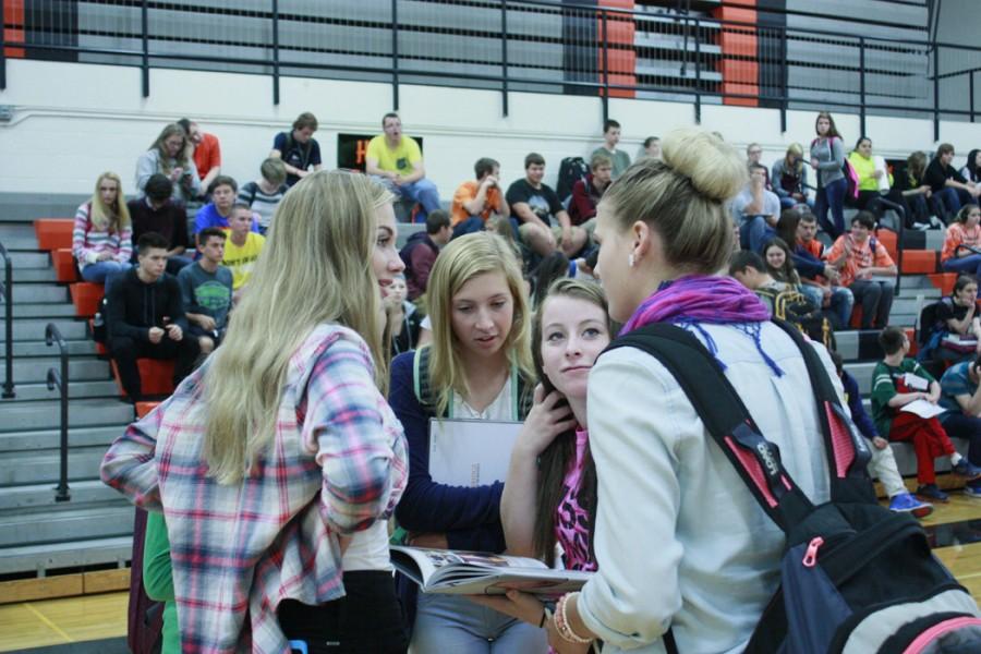 Sharing a first glimpse  of the 2015 yearbook, junior Alexis Roberts talks to  Shaylyn Sprout 11  while  sophomores Kaylee Samulak and Faith Whitt look at the Capture yearbook at distribution day.