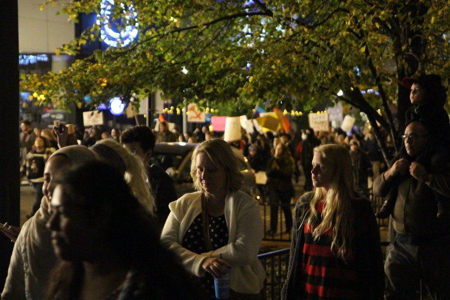 People of all different backgrounds walk down the sidewalk, chanting three haunting words: “Not my president.”
