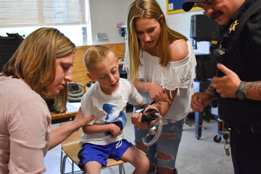 A perfect fit. Ezra’s parents watch as freshman Chelsea Asquith puts the fishing rod in Ezra’s hand for him to test out the feel of it. PHOTO KAITLIN MILLER.