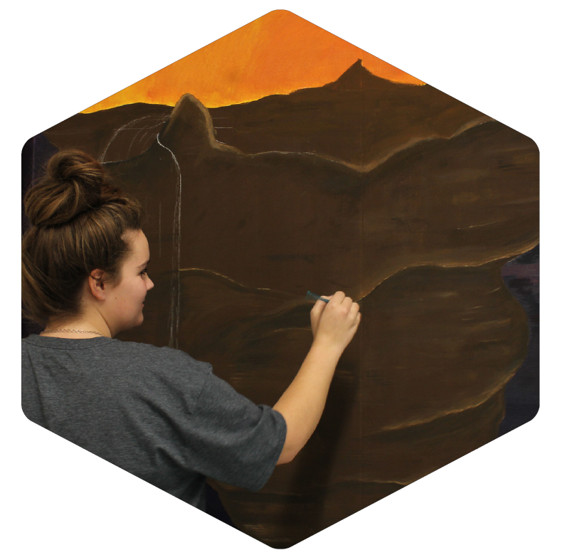 With a paintbrush in hand, senior Arianna Place adds art to the school walls.
