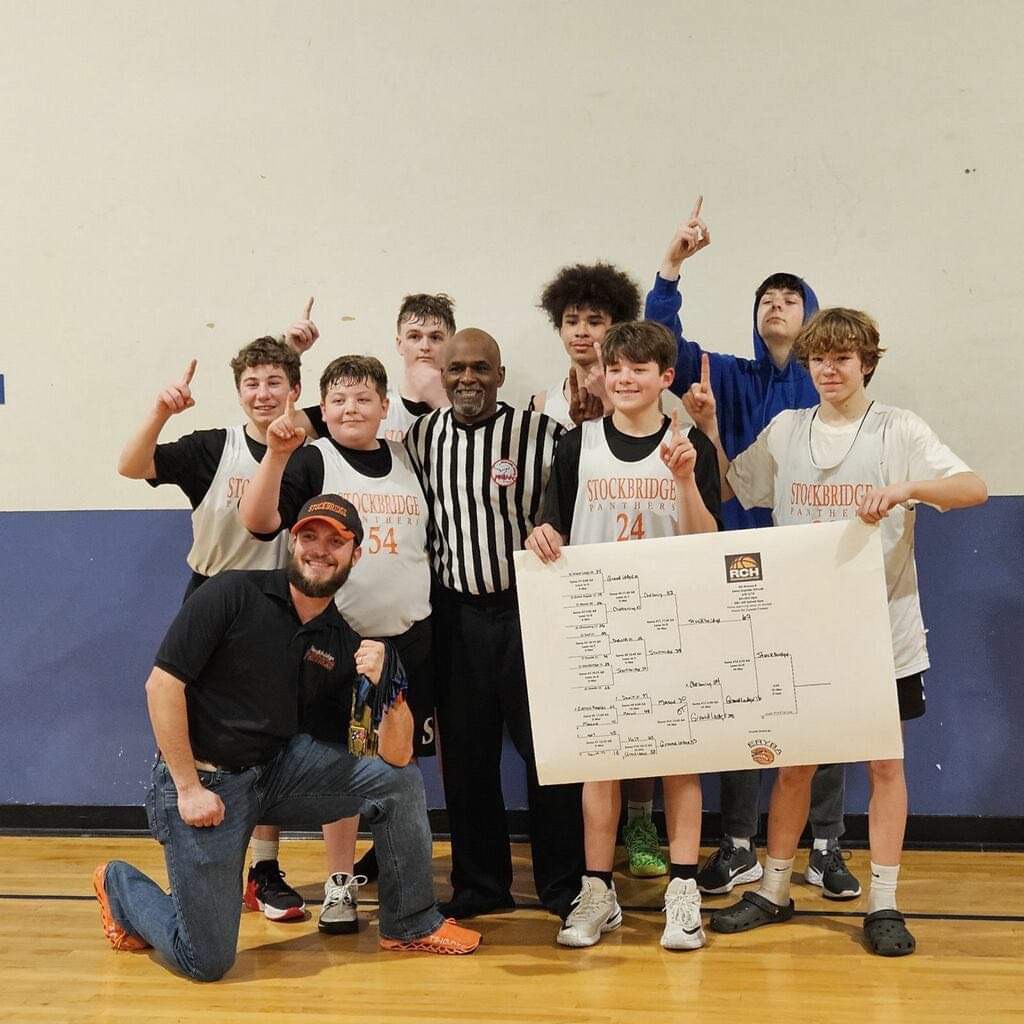 The team celebrates their tournament win with coach Mayville. Photo used with permission from Kristine Regan. 