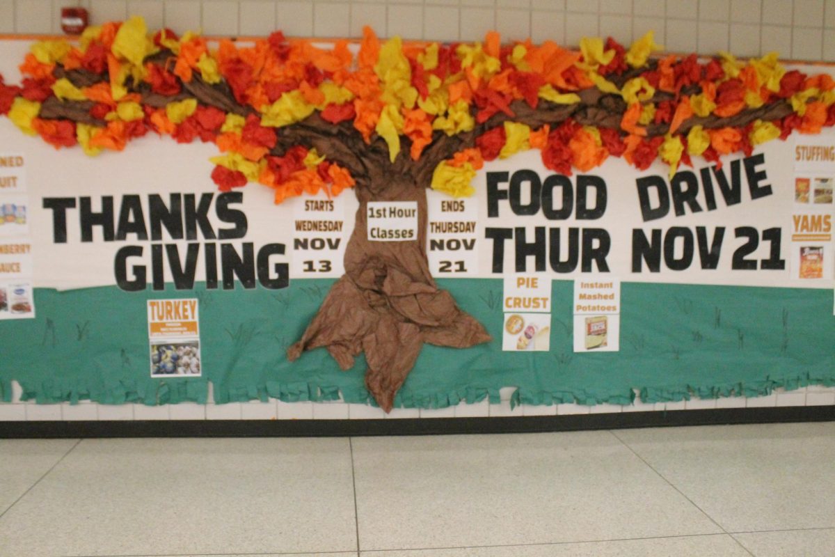 The bulletin board in the cafeteria with information about the school food drive. 