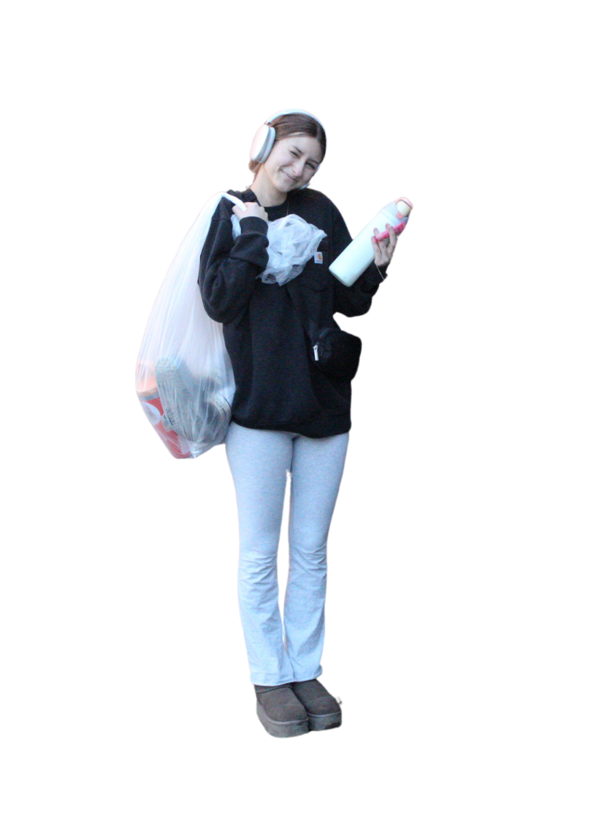 Miley Moser poses with the latest trending items while holding items that are considered "Out" in a trash bag. 